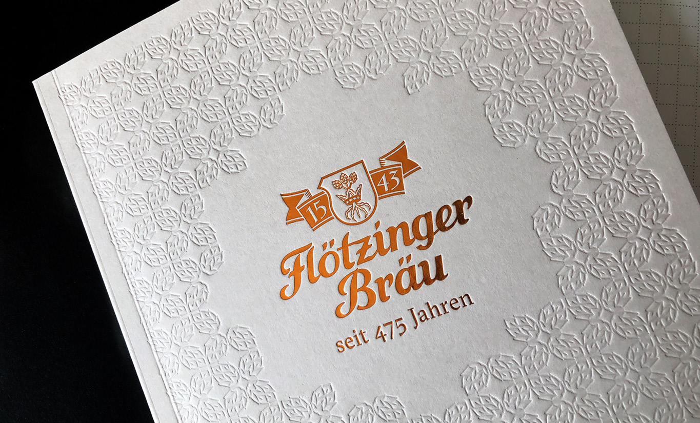 Die Imagebroschüre für die 475 Jahre Feier. Logo Flötzinger Bräu in kupferfarbener Folie auf beigem Karton. Ein Muster auf Hopfen in Blindprägung im Hintergrund.